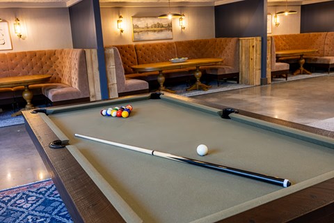 A pool table with a white ball and a cue stick on it.