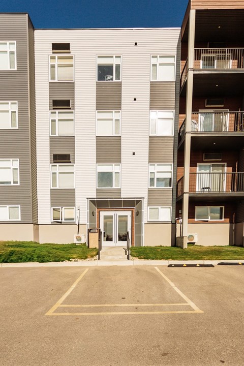 A large apartment building with a parking lot in front.