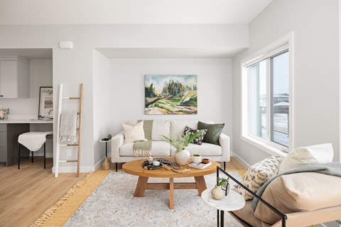 A living room with a white couch, a coffee table, and a painting on the wall.