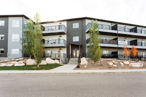 Apartment building with a grey and black exterior and a balcony on the second floor.