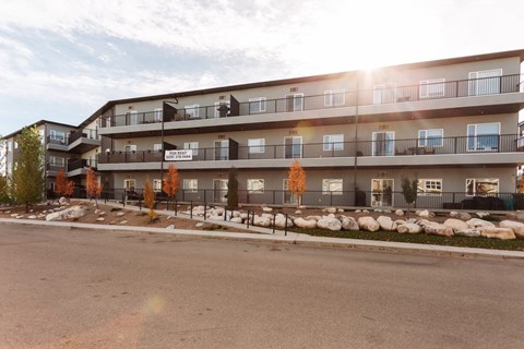 Apartment complex with a parking lot in front.