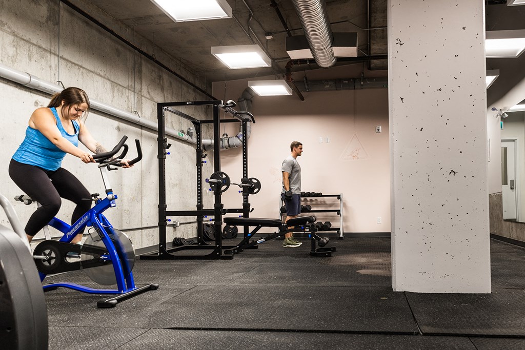 a man and a woman riding exercise bikes in a gym
