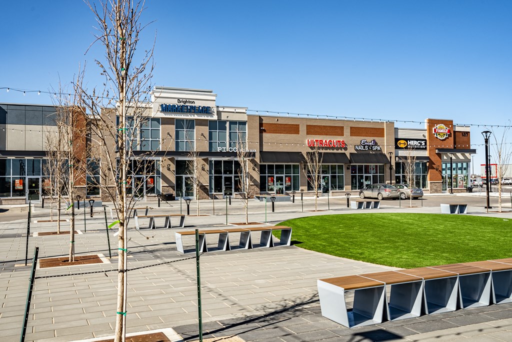 a city square with benches and a lawn in front of a building