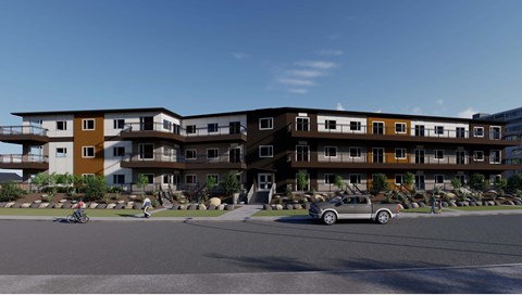 A modern apartment complex with cars parked in front.