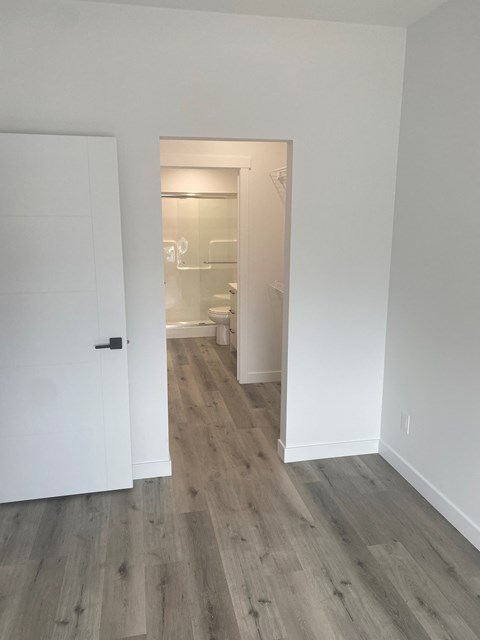 a bedroom with white walls and a door to a bathroom