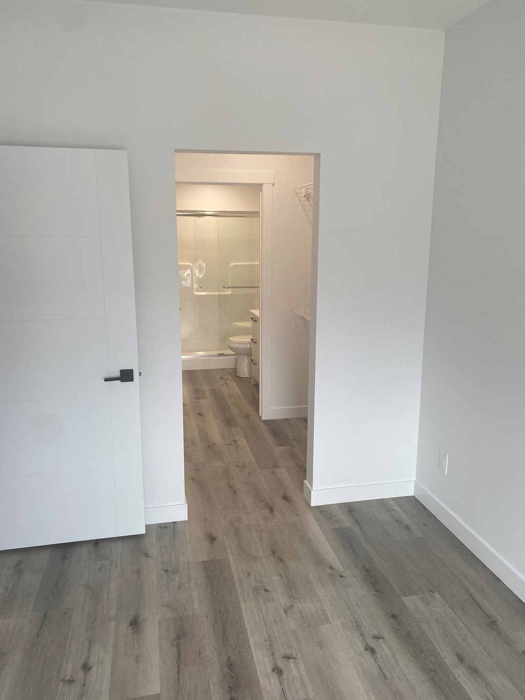 a bedroom with white walls and a door to a bathroom