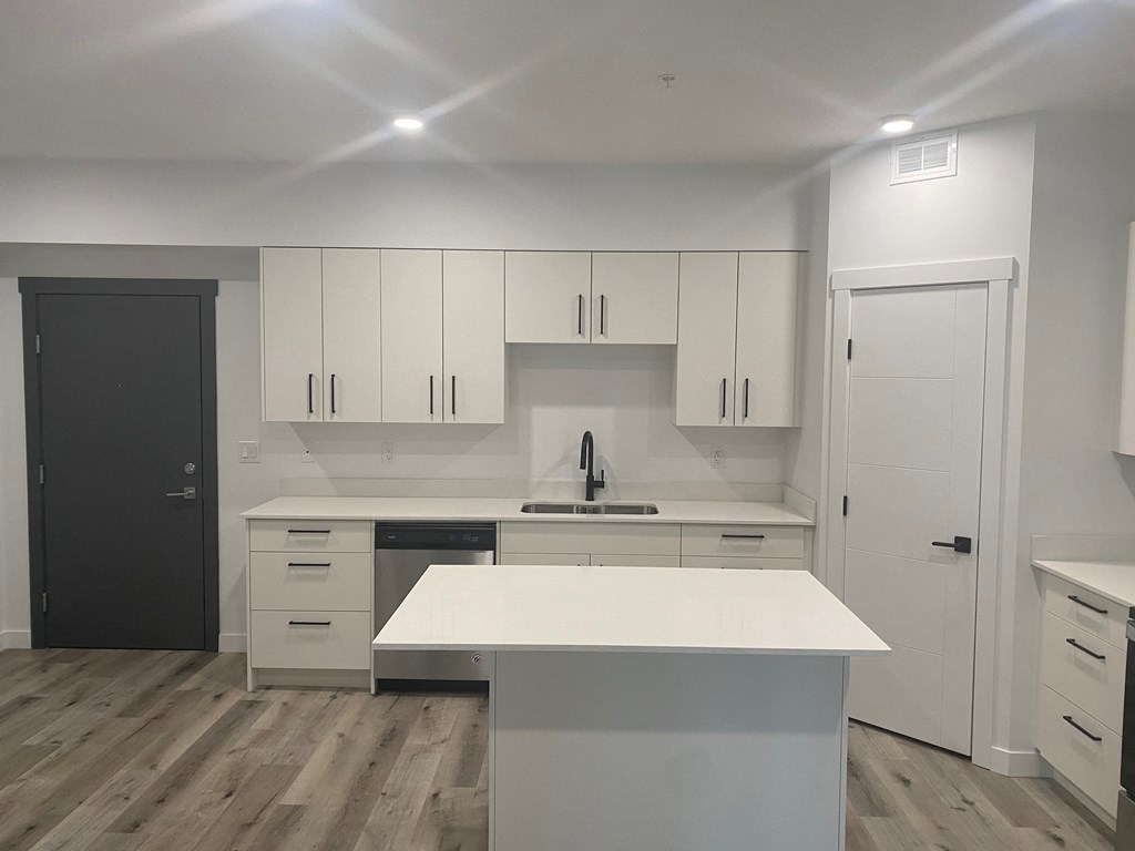 an empty kitchen with white cabinets and a white counter top