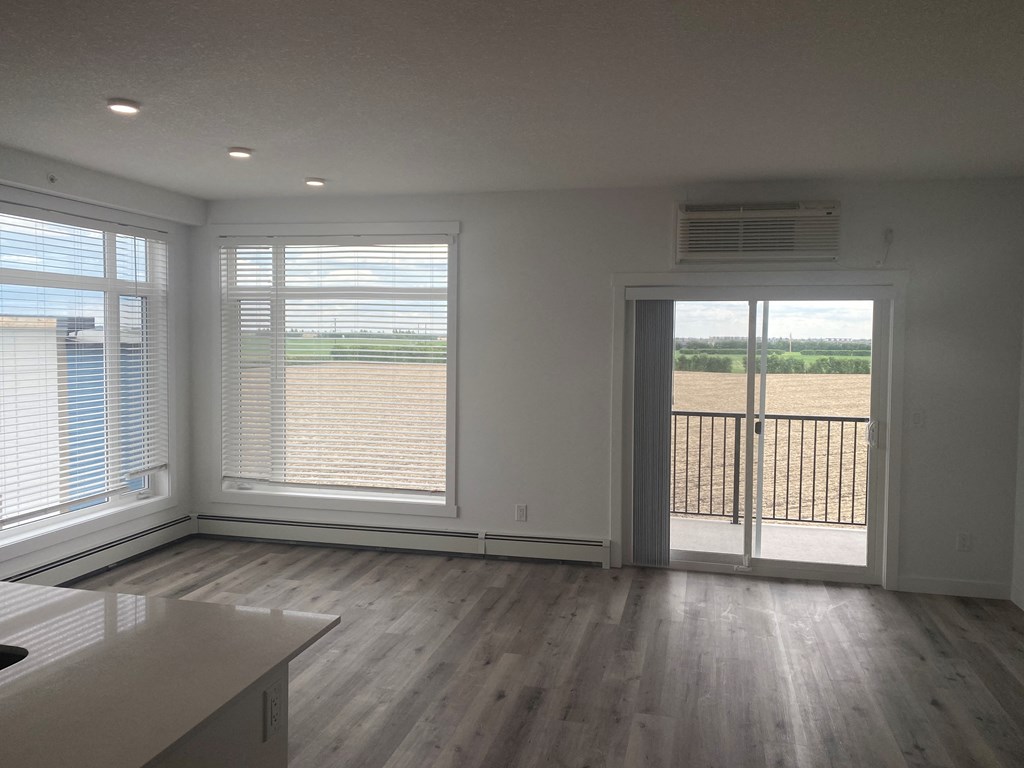 a living room with wood floors and a door to a balcony