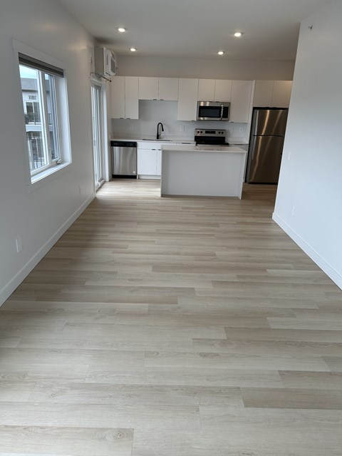 A kitchen with white cabinets and a wooden floor.