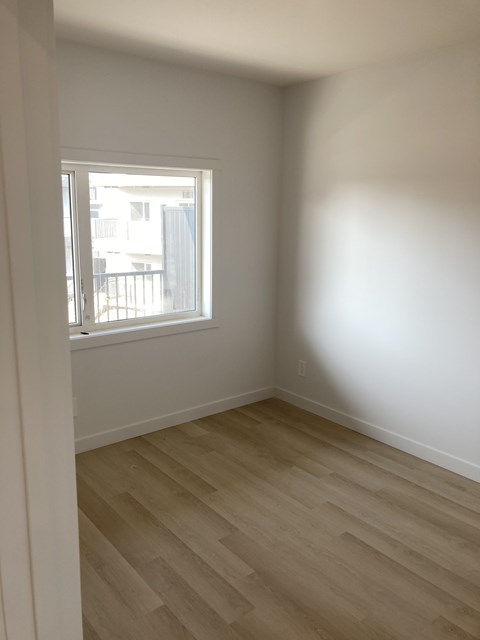 A room with a window and wooden flooring.