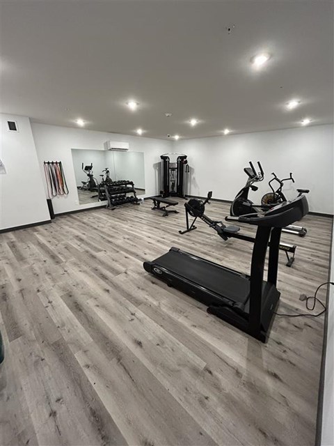 A gym with a variety of equipment including treadmills, weights, and exercise machines.