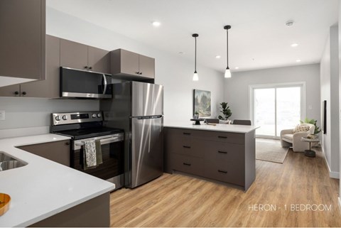 A modern kitchen with a stainless steel refrigerator and oven, and a dining area with a table and chairs.