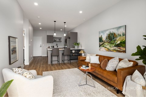 A living room with a brown couch and a painting on the wall.