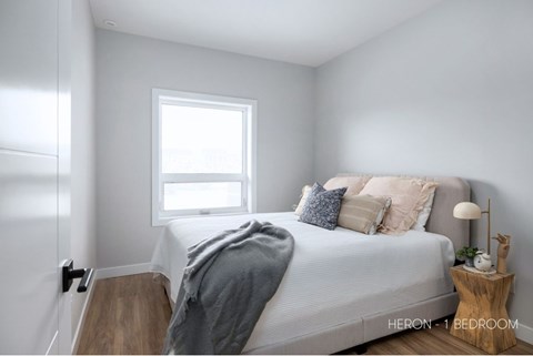 A bedroom with a bed, a window, and a lamp on a side table.