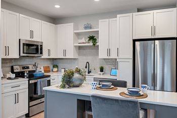 a kitchen with white cabinets and stainless steel appliances and a white counter top at Preston Ridge, Cary, 27513
