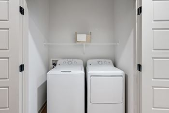 Two white washing machines in a small laundry room.