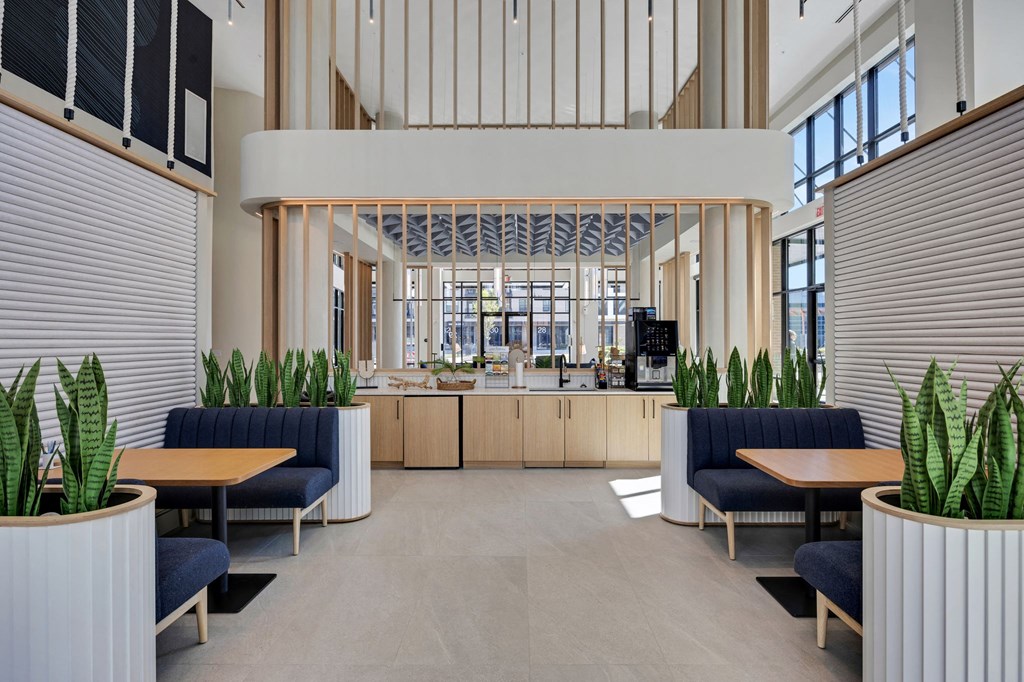 the lobby of a building with blue chairs and tables and a large window at Metropolitan at the Riverwalk, Wilmington, NC