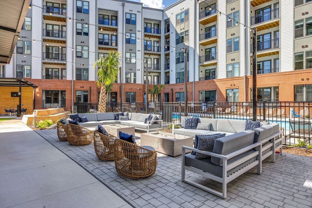 an outdoor lounge area with couches and chairs in front of an apartment building at Metropolitan at the Riverwalk, Wilmington, NC