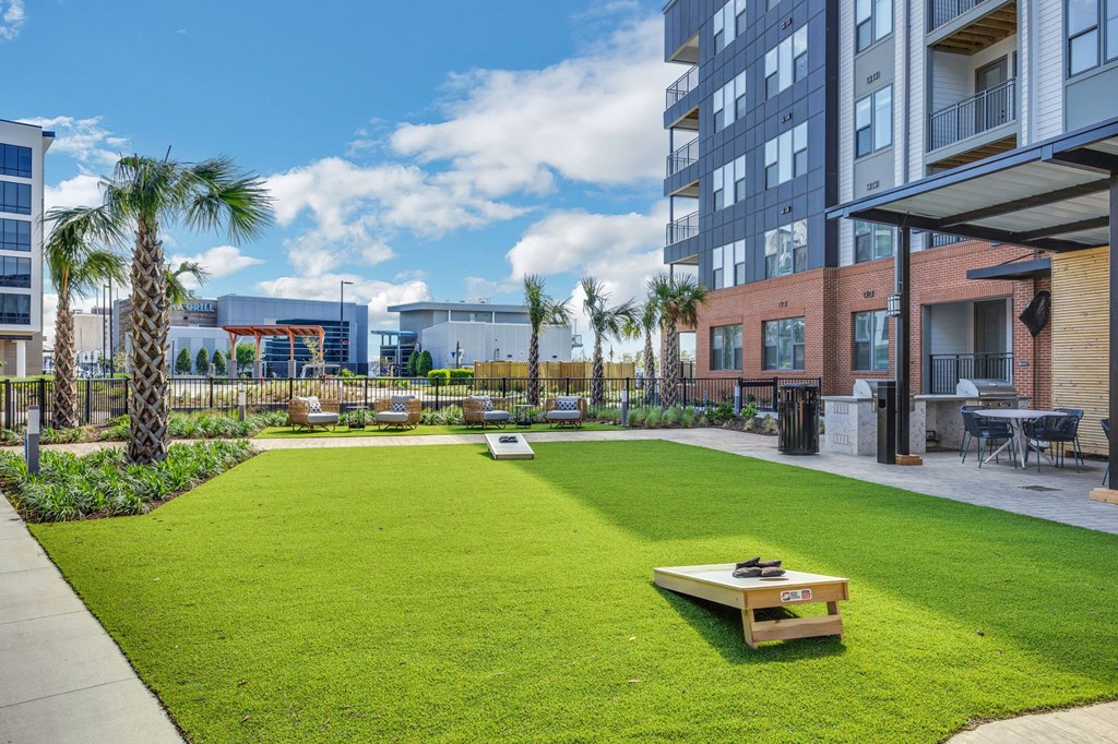 a yard with grass and palm trees in front of a building at Metropolitan at the Riverwalk, Wilmington, NC