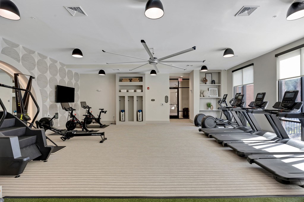 a gym with treadmills and a tv on the wall at Metropolitan at the Riverwalk, Wilmington, NC