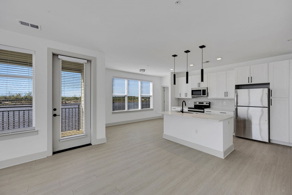 a white kitchen with a large island and a stainless steel refrigerator at Metropolitan at the Riverwalk, Wilmington