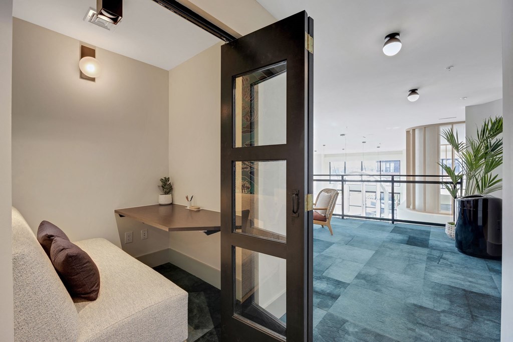 a living room with a desk and a door to a balcony at Metropolitan at the Riverwalk, Wilmington, NC