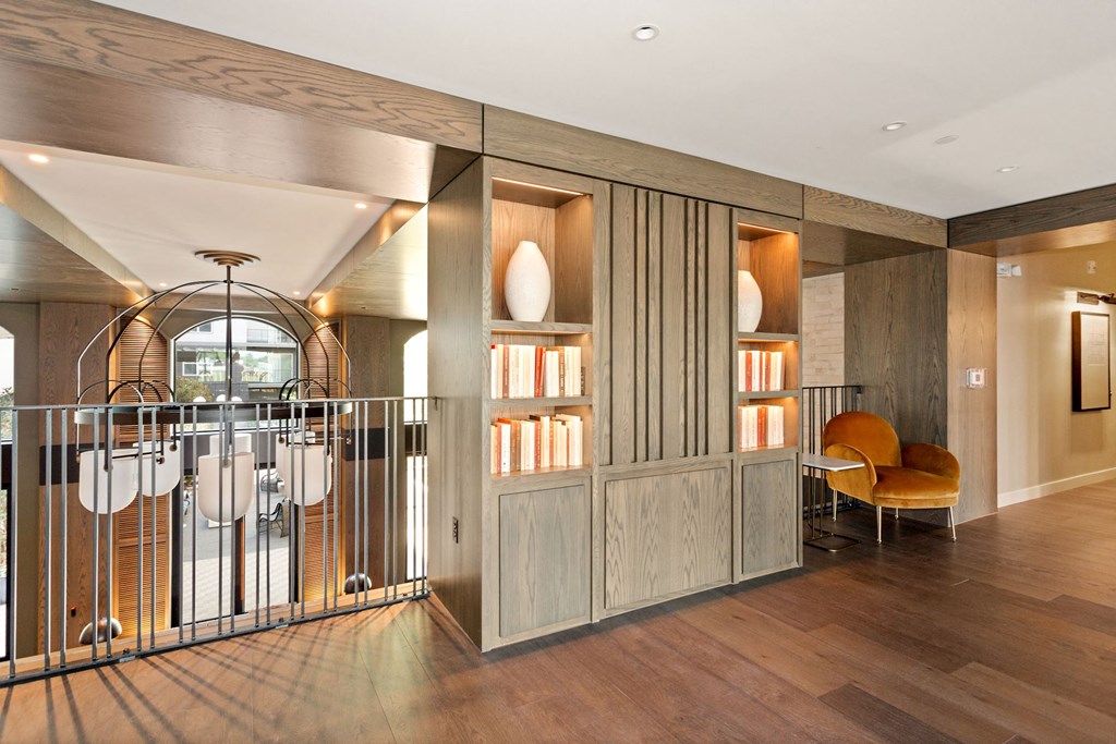 a room with wood floors and a wrought iron railing with a chair and bookshelf at Vyne One Loudoun, Ashburn, Virginia