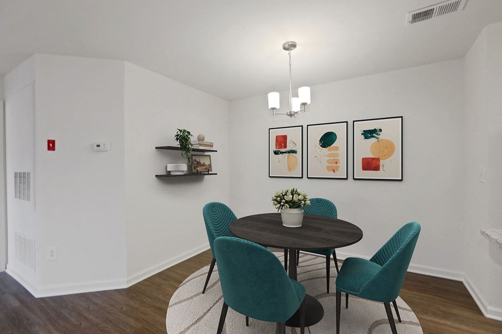 a dining room with a round table and four green chairs