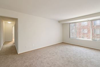 an empty living room with a large window and carpeting