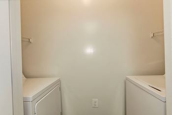 an empty laundry room with a washer and dryer and a sink at County Center Crossing Apartments in Woodbridge, VA