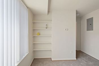 a bedroom with white walls and shelves and a window