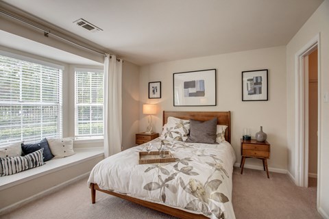 the master bedroom has a large window and a comfy bed