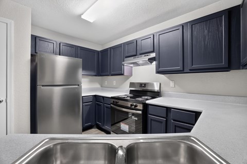 A kitchen with dark blue cabinets and stainless steel appliances.
