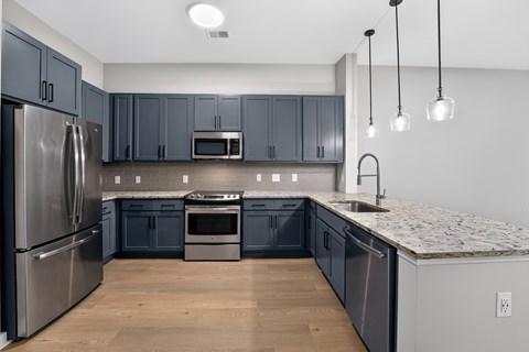 A kitchen with dark blue cabinets and stainless steel appliances.
