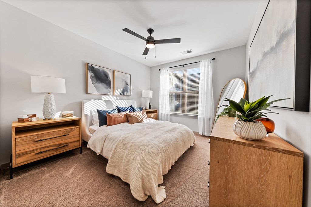 A bedroom with a bed, dresser, and ceiling fan