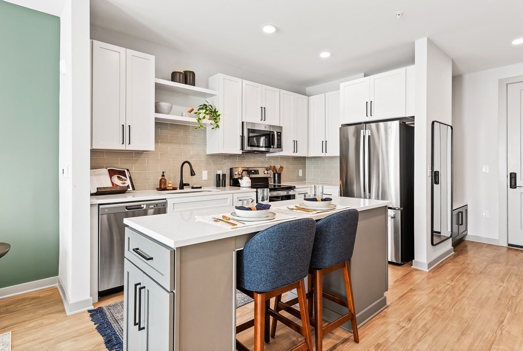 A kitchen with a white countertop and a stainless steel refrigerator