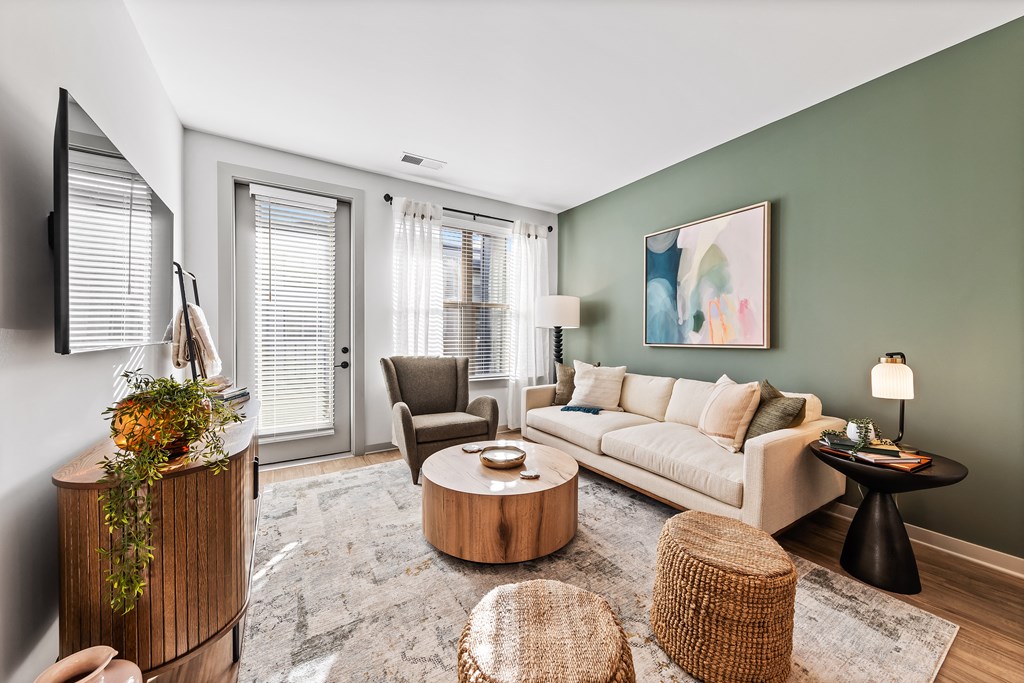 A living room with a white sofa, a wooden coffee table, and a TV on the wall