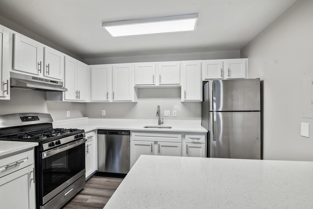 A kitchen with white cabinets and a stainless steel refrigerator at Shenandoah Station Apartments, Triangle, VA