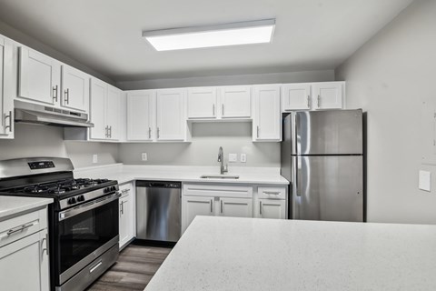 A kitchen with white cabinets and a stainless steel refrigerator.
