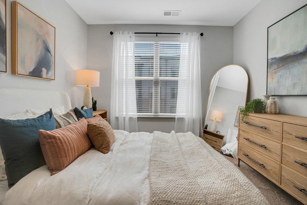 a bedroom with a large bed and a mirror a bedroom with a large bed and a mirror at Preston Ridge, Cary
