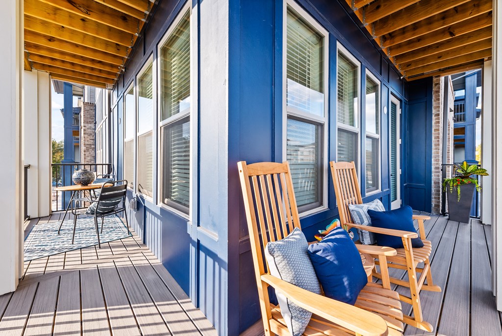 A balcony with wooden chairs and a table