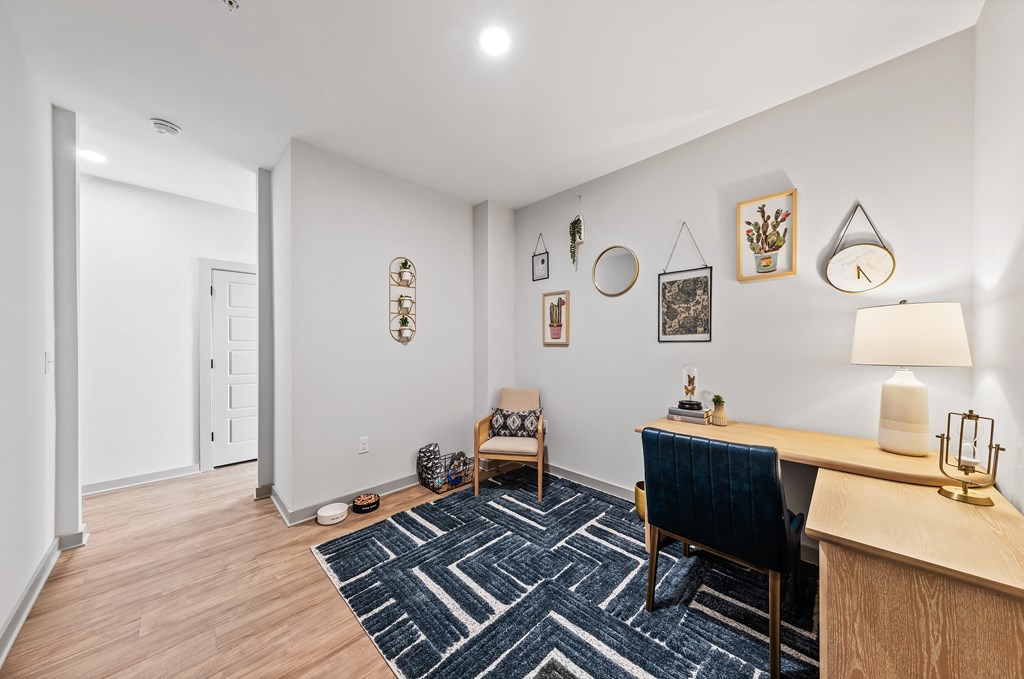 A room with a blue chair and a desk with a lamp on it