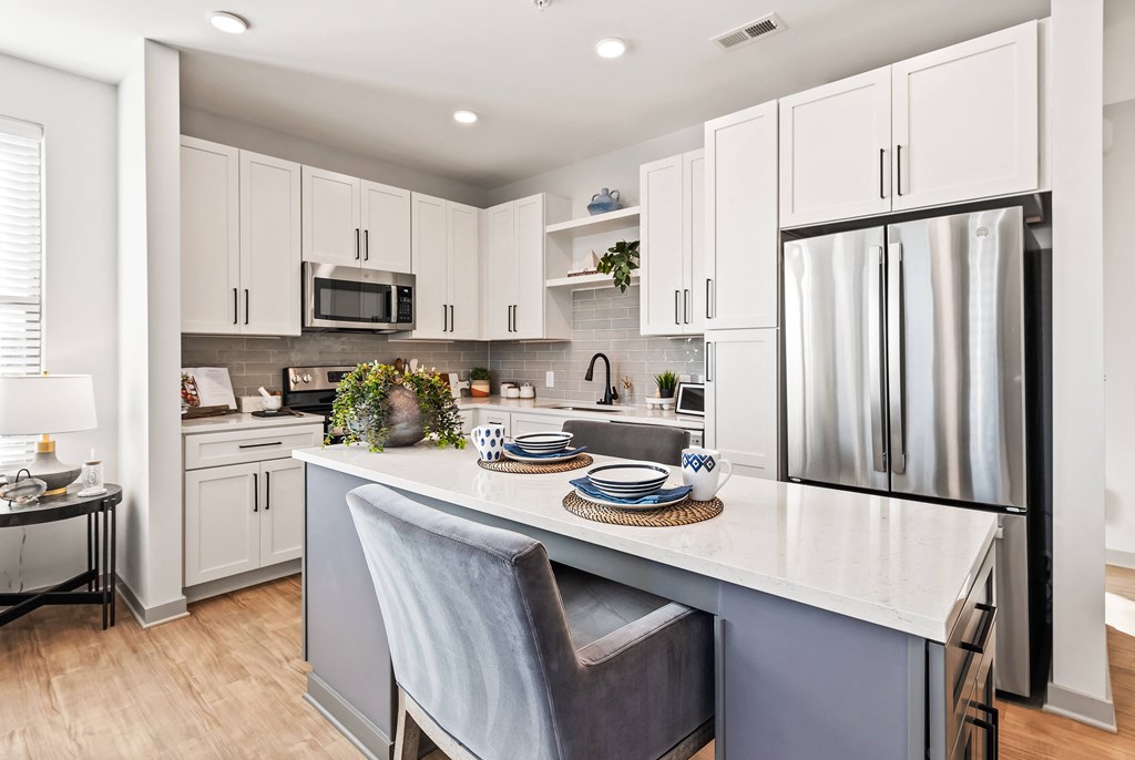 A kitchen with a white countertop and a grey chair