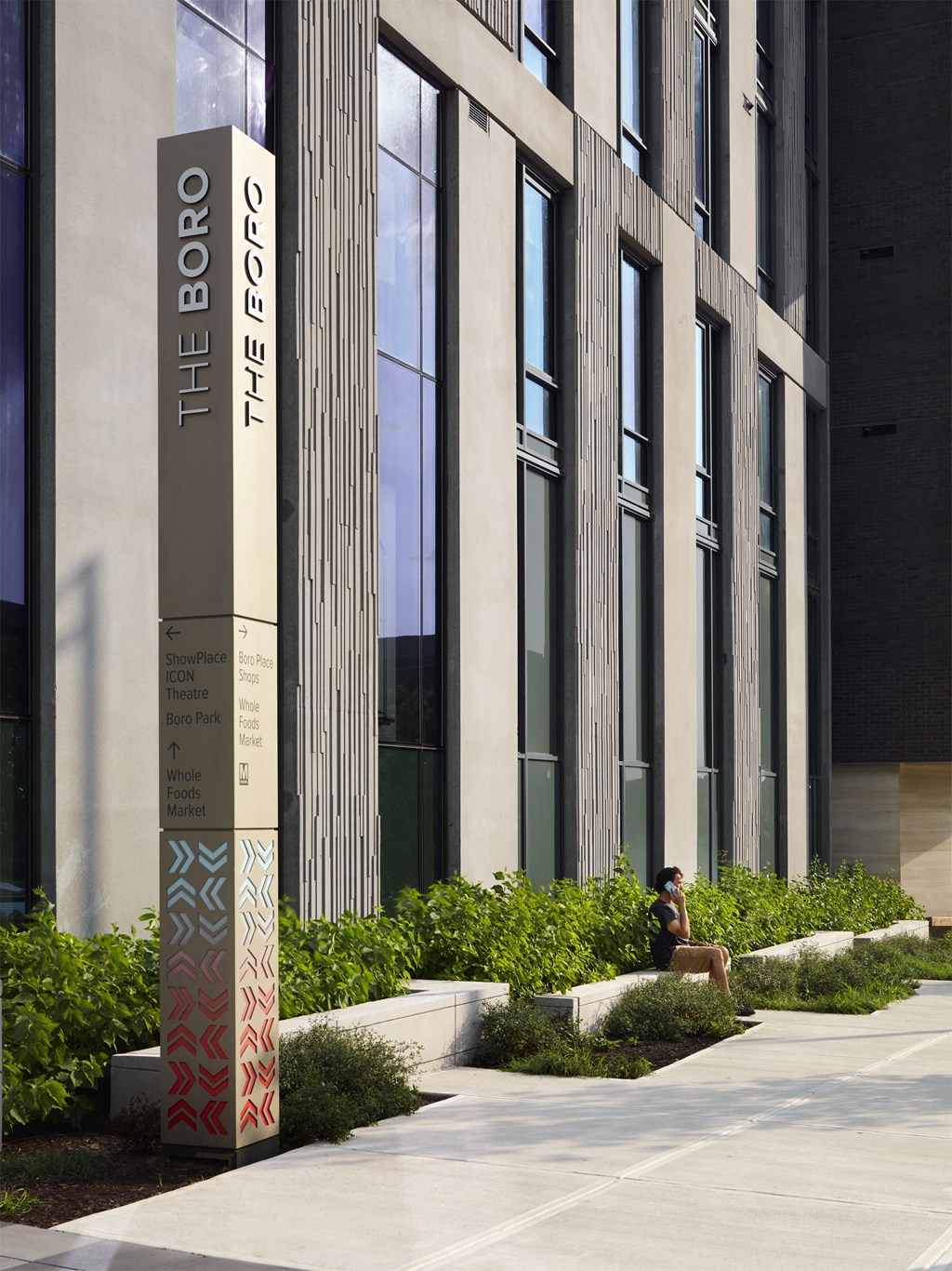 a person sitting on a bench in front of a building at The Boro, Tysons, 22102