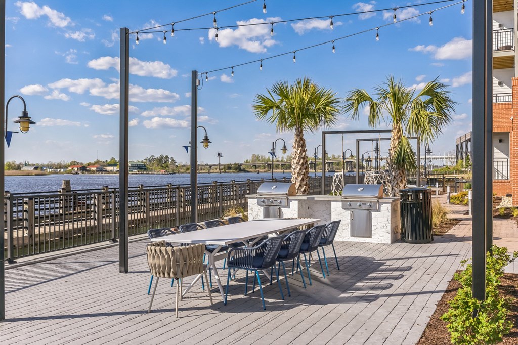 a patio with a table and chairs and a bar and a body of water at Metropolitan at the Riverwalk, Wilmington, NC