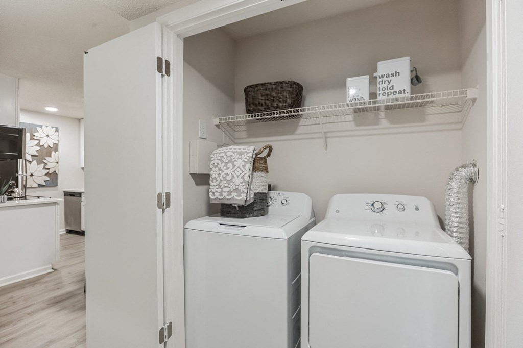 a white washer and dryer in a laundry room with a shelf above it at St. Andrews Reserve, Wilmington, NC
