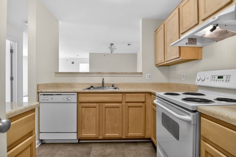 A kitchen with a white stove and wooden cabinets.