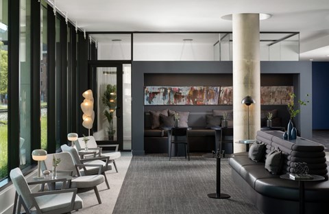 A modern living room with a black couch and grey chairs.
