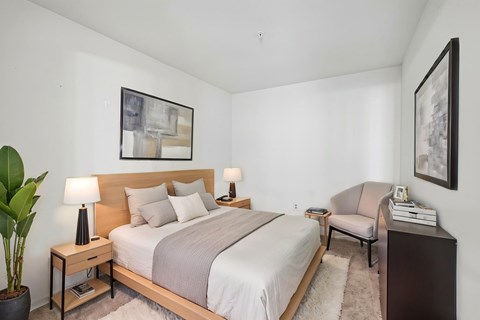 A bedroom with a large bed and a chair.
