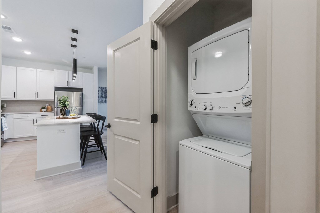 a laundry room with a washer and dryer and a kitchen with white cabinets at the Riverwalk, Wilmington